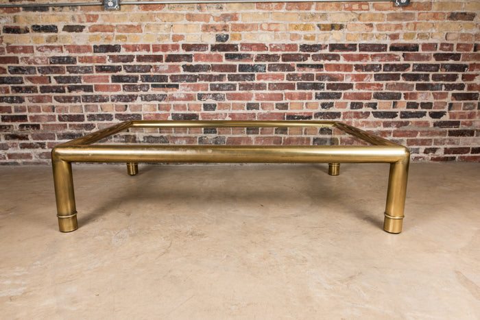 A beautiful, substantial, square brass and glass coffee table by Mastercraft. Thick tubular brass frame with subtle ring detail at the base of each leg.